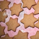 Golden brown, star-shaped biscuits are on a white baking sheet
