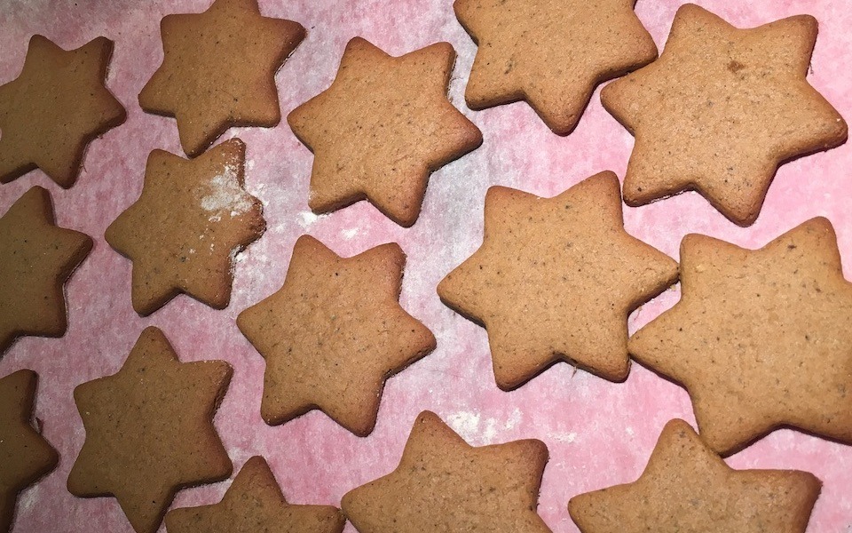 Golden brown, star-shaped biscuits are on a white baking sheet